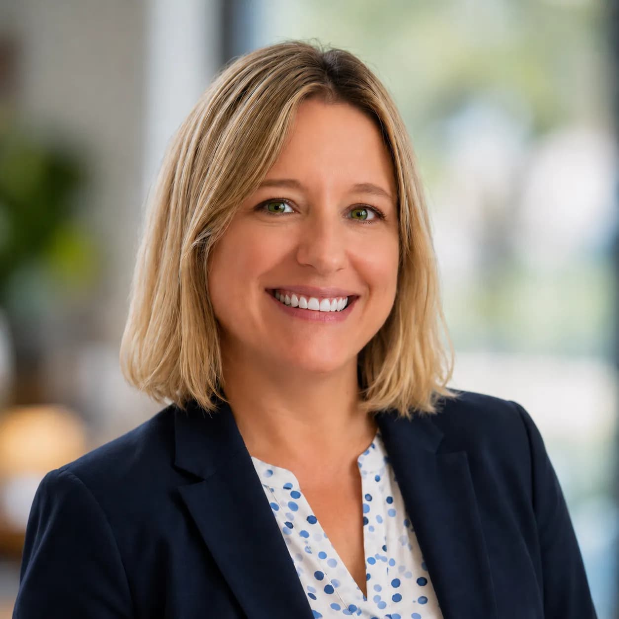 Adrienne Gildea smiling in a blue blazer against an office background.