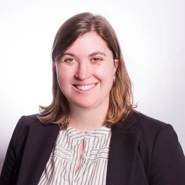 Margaret Edwards Velasquez smiling in a black blazer against a white office background.
