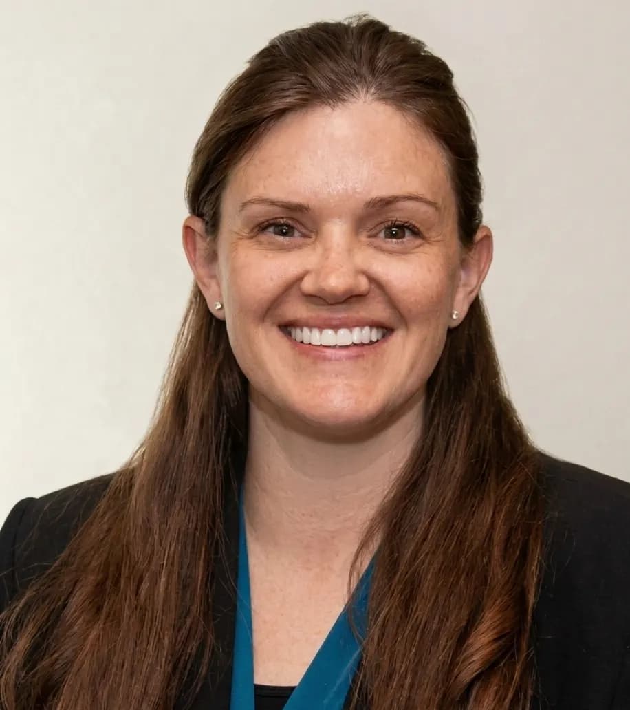 Shannon Heck smiling in a blue blazer against a white office background.